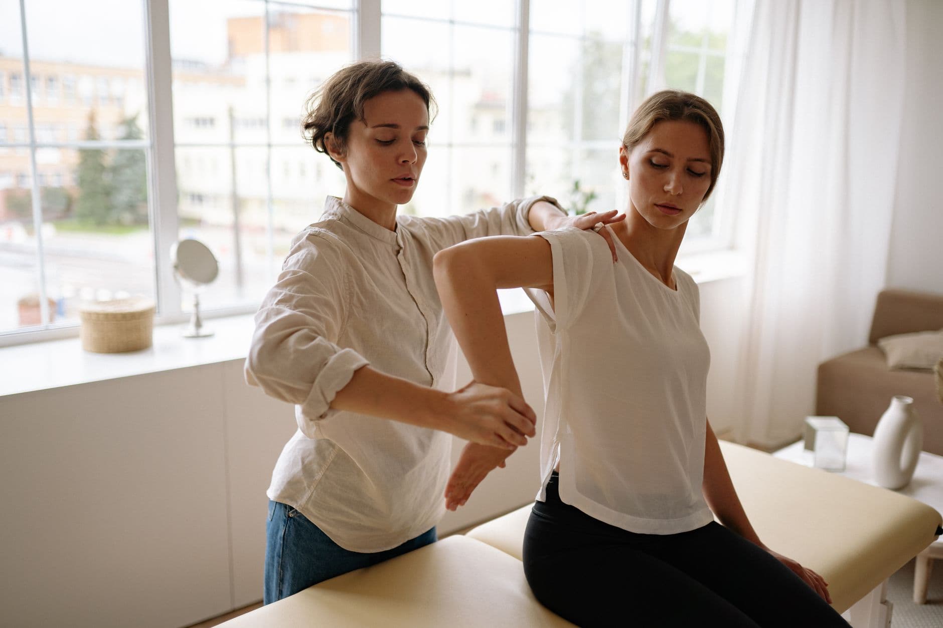 Une professionnelle de la santé aide une femme lors d'une séance à l'intérieur, lumière naturelle.