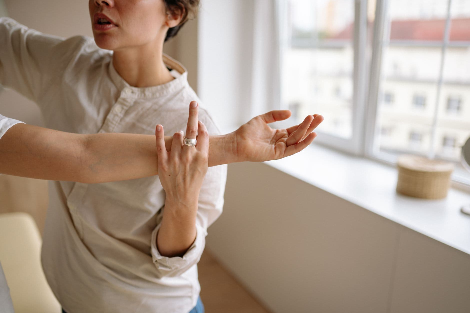 Une femme en haut clair fait un mouvement de bras, tandis qu’une autre main semble guider ou toucher son avant-bras d…